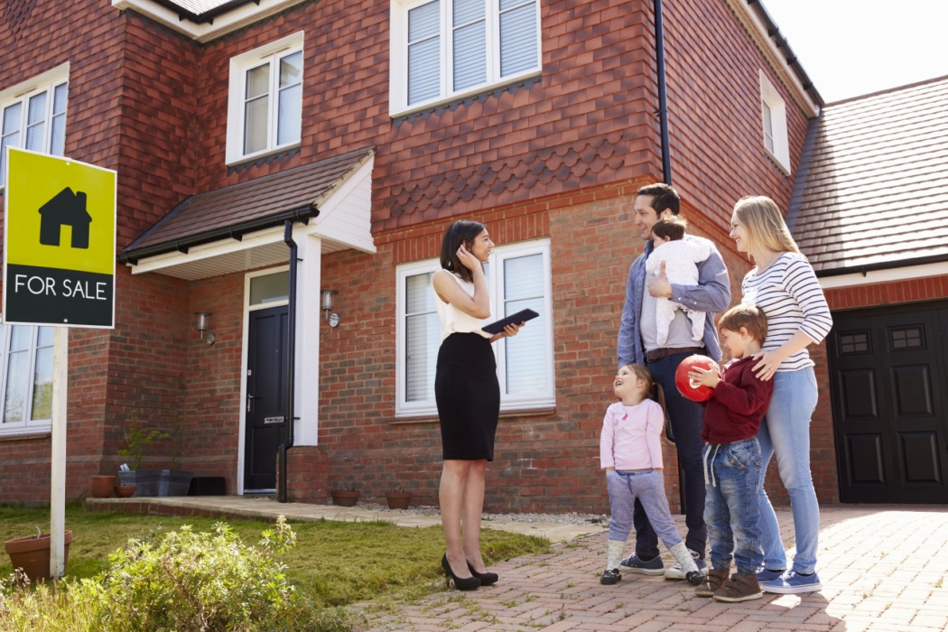 A family standing outside a house with a real estate agent.