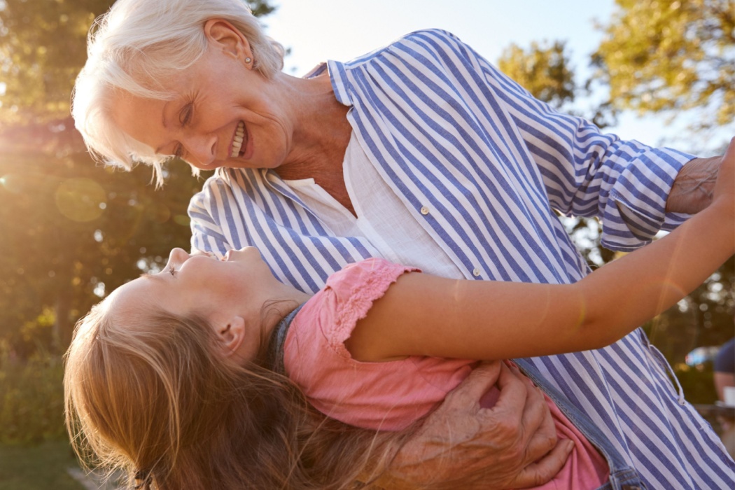 A grandmother playing with her granddaughter outside.