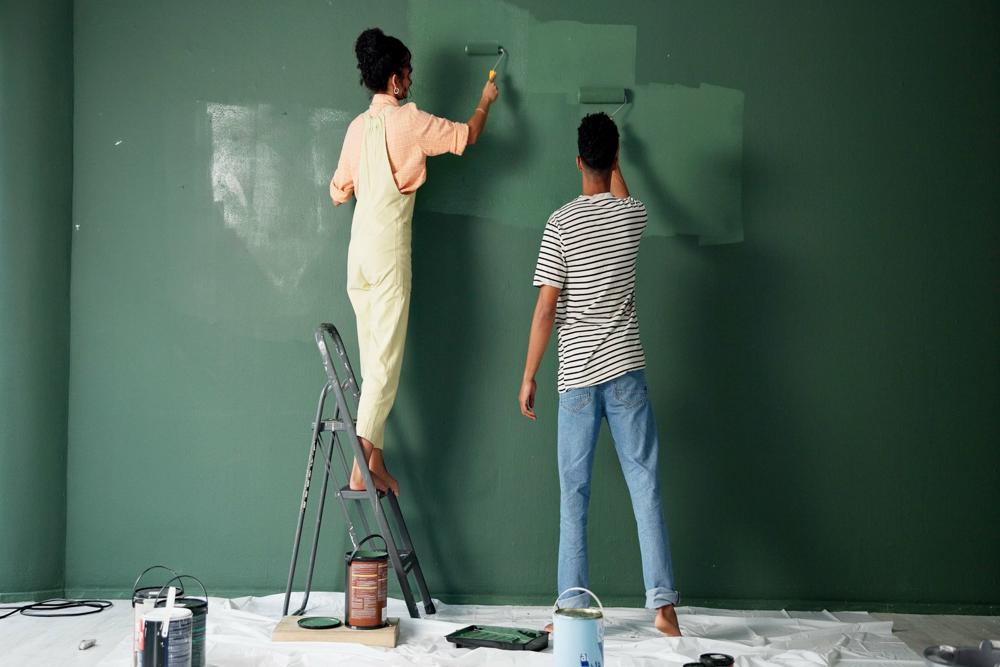 A couple painting a wall green