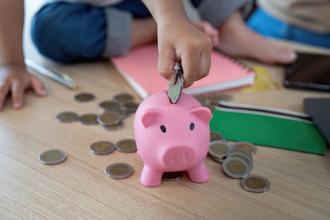 Child putting coins into a piggy bank